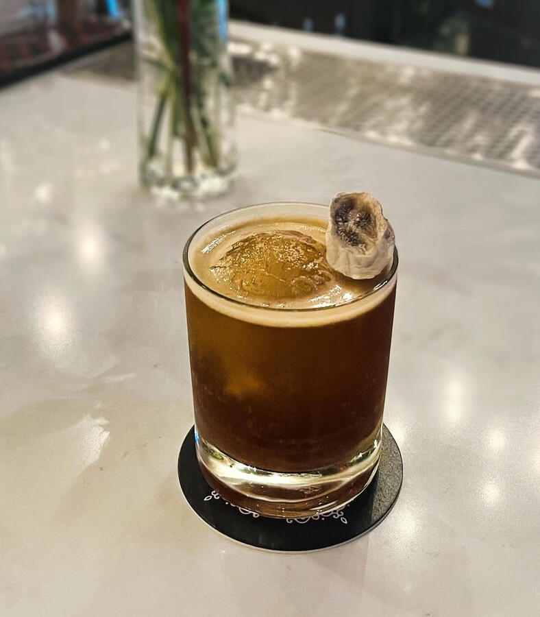 Bumbu Rum, Amaro Averna, Fion Sherry, banana syrup, orange juice, coffee, ginger bitters, Aztec chocolate bitters, dehydrated banana